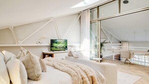 Une chambre moderne avec un grand lit, une télévision et un balcon offrant une vue agréable.
