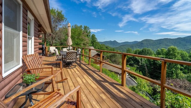 A wooden deck with outdoor furniture, a covered table, and a view of mountains. - Whisper Mountain Retreat (Franklin)