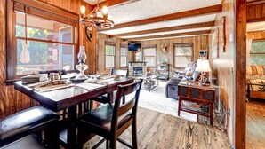 A wooden interior with a dining area, a fireplace, and a cozy seating area. - Whisper Mountain Retreat (Franklin)