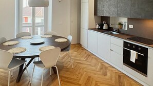 Ett modernt kök med en stor köksö, vita skåp och ett trägolv med fiskbensmönster.