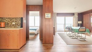 A spacious room with wooden flooring, a dining area with a table and chairs, and a kitchen with wooden cabinets. - Kona Farm Stay - Amazing Ocean and Sunset Views (Kailua-Kona)