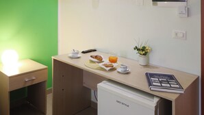 A kitchenette with a GIO'STYLE refrigerator, a small table with a book, a cup, a plate with a pastry, and a pitcher of orange juice. - B&B GreenWave (Monopoli)
