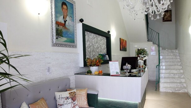A reception area with a sofa, a desk, a chandelier, and a staircase. - B&B GreenWave (Monopoli)