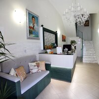 Un'area reception con una poltrona, una scrivania, un lampadario e una scala.