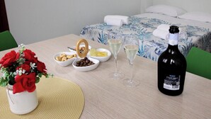 A hotel room with a bed, a table with food and drinks, and a bottle of wine. - B&B GreenWave (Monopoli)