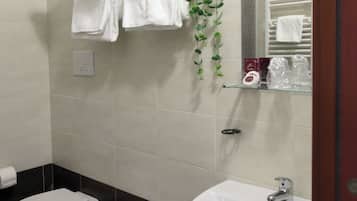 Un bagno con bidet, lavandino e porta asciugamani con asciugamani piegati.