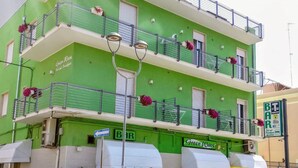 A multi-story building with balconies, a bar area, and outdoor seating. - B&B GreenWave (Monopoli)