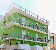 Un edificio a più piani con balconi, un'area bar e posti a sedere all'aperto.