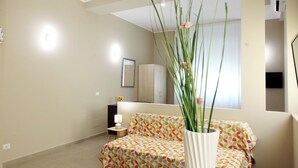 A modern hotel room with a bed, a small bedside table with a lamp, a wardrobe, and a large window with a view. - B&B GreenWave (Monopoli)