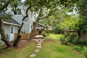 A house with a covered porch, a stone pathway leading to the entrance, and a bench in the yard.