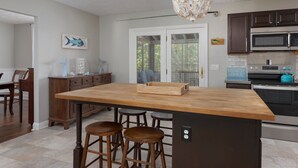 Une cuisine dotée de plans de travail en bois, de tabourets de bar, d’un lustre et d’appareils électroménagers modernes.