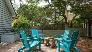 Une terrasse avec quatre chaises Adirondack turquoise et une table en bois.