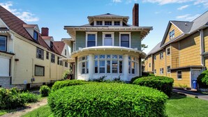 Une maison à deux étages avec une véranda qui fait le tour de la maison et une baie vitrée.