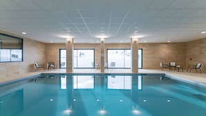A swimming pool with clear water, surrounded by tiled walls and windows. - Studio cosy au pied des pistes | Piscine + sauna (Piau-Engaly)