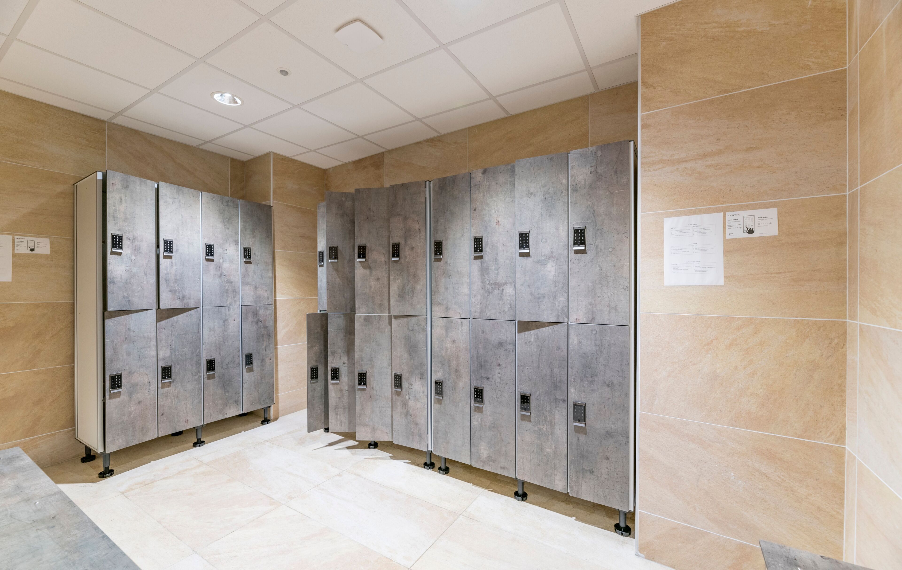 Een rij metalen lockers met een betegelde vloer en muren.