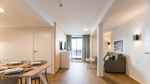 A modern apartment with a dining area, a living room with a sofa, and a balcony with a view.
