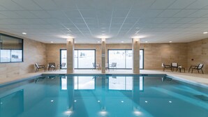 A swimming pool with clear water, surrounded by tiled walls and windows.