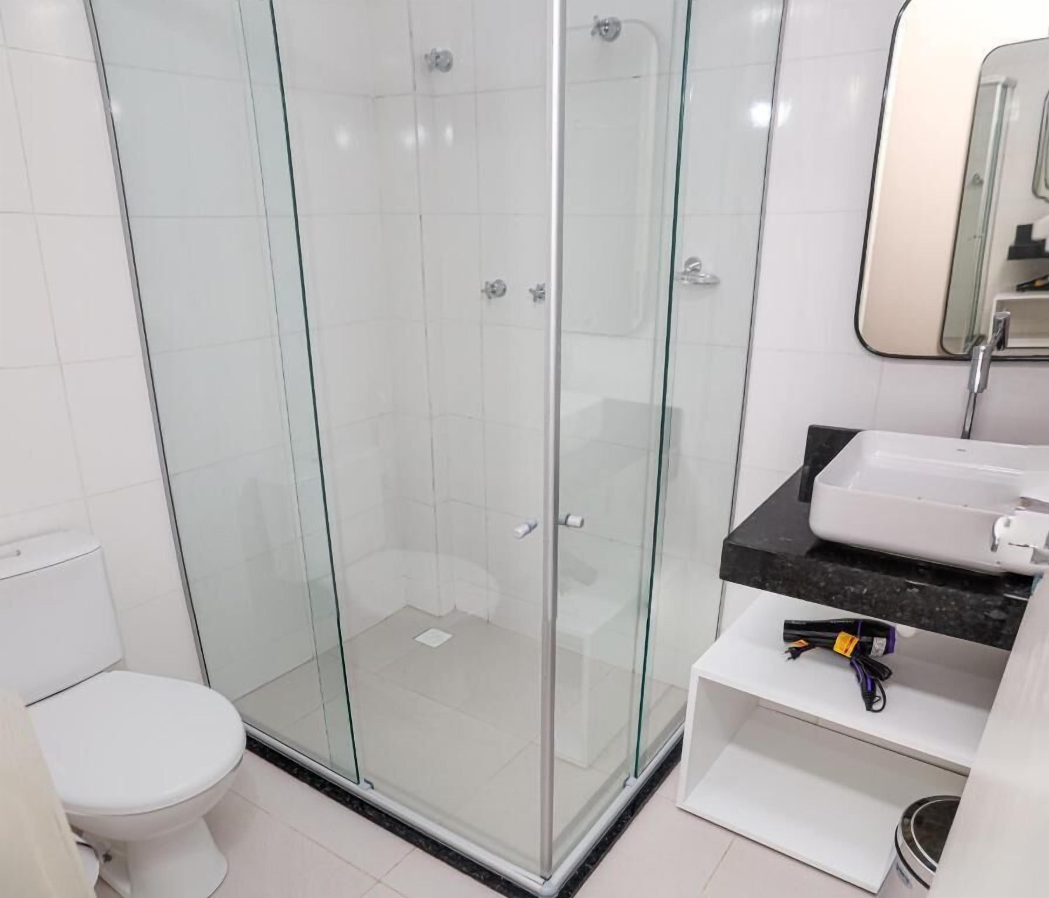 A bathroom with a glass-enclosed shower, a white toilet, and a sink with a black countertop.