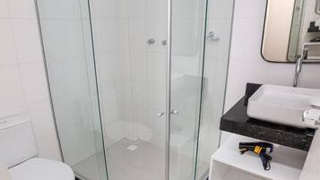 Un baño con ducha de vidrio, inodoro blanco y lavamanos con encimera negra.