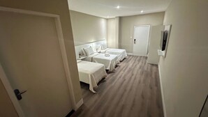 A hotel room with three beds, a TV, and a door. - Amazon Park Hotel (Belém)