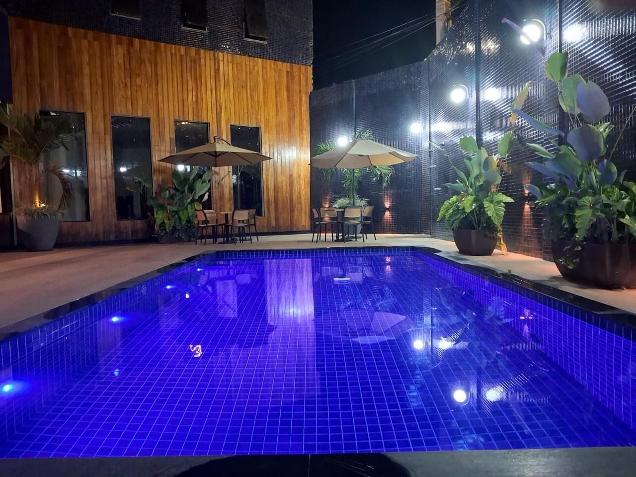 Ein Innenpool mit blauer Beleuchtung, umgeben von Holzwänden und Topfpflanzen.
