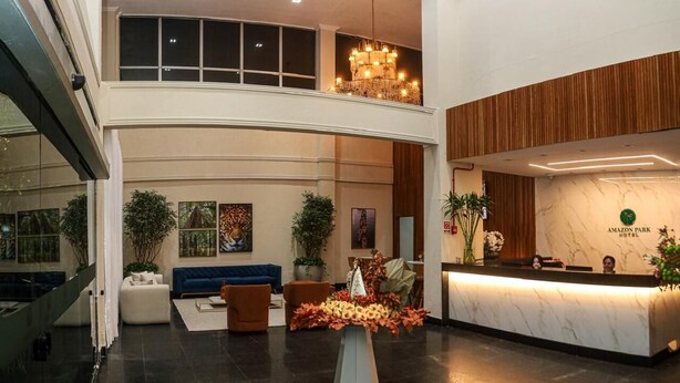 A hotel lobby with a reception desk, seating area, and a staircase leading to an upper level. - Amazon Park Hotel (Belém)