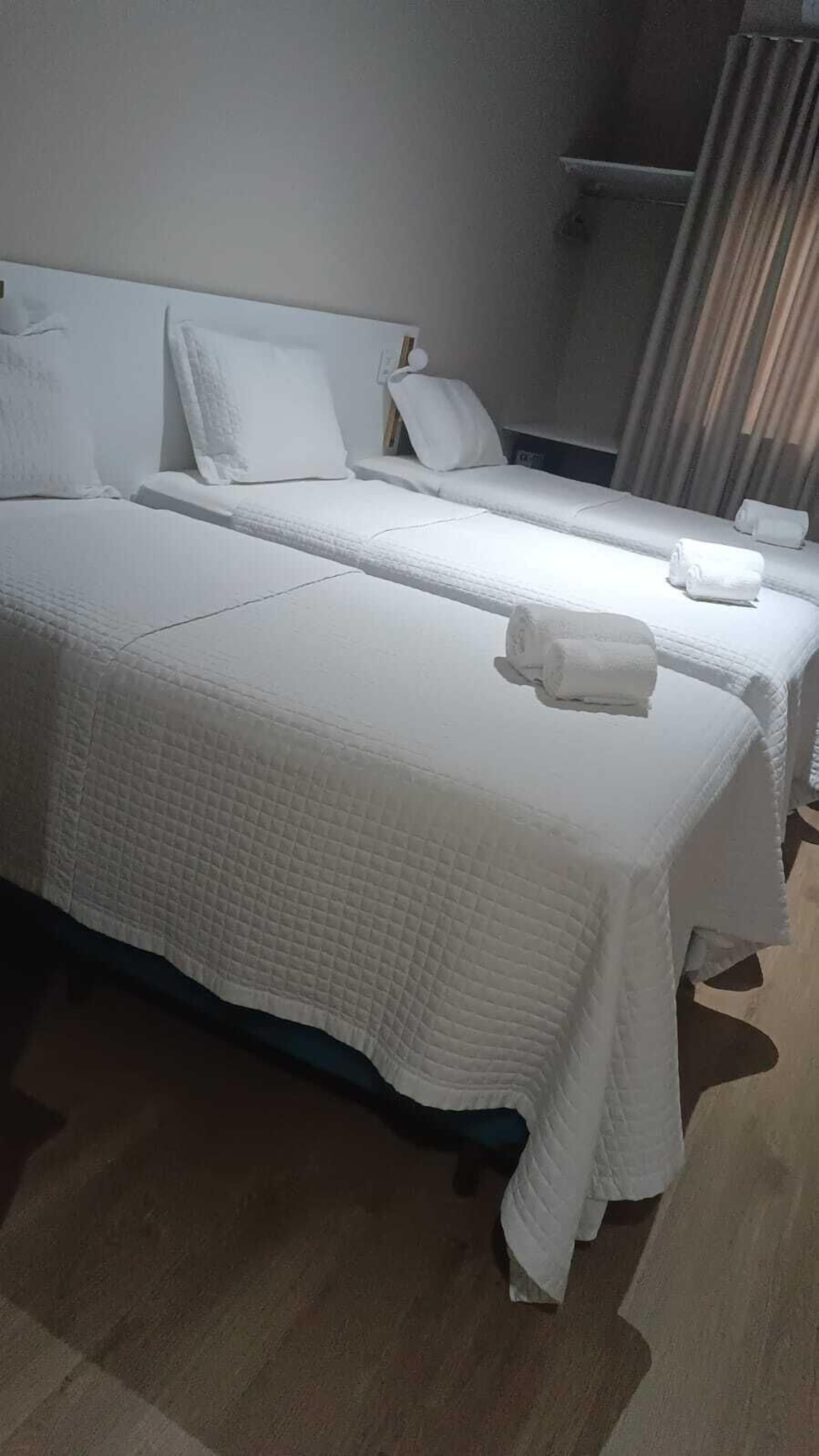 Una habitación de hotel con dos camas, cada una con ropa blanca y almohadas.