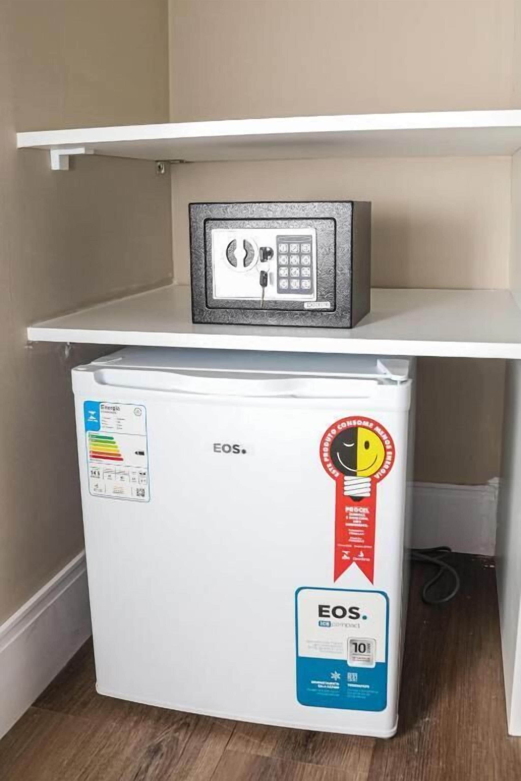 A white refrigerator with a freezer compartment, a small safe on top, and a red sticker indicating a 10-year warranty.