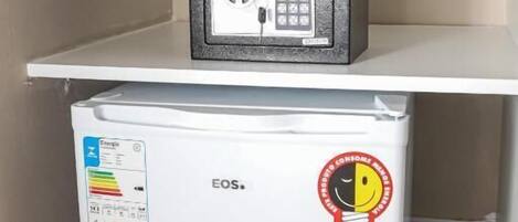 Een witte koelkast met een vriesvak, een klein kluisje bovenop, en een rode sticker met vermelding van 10 jaar garantie.