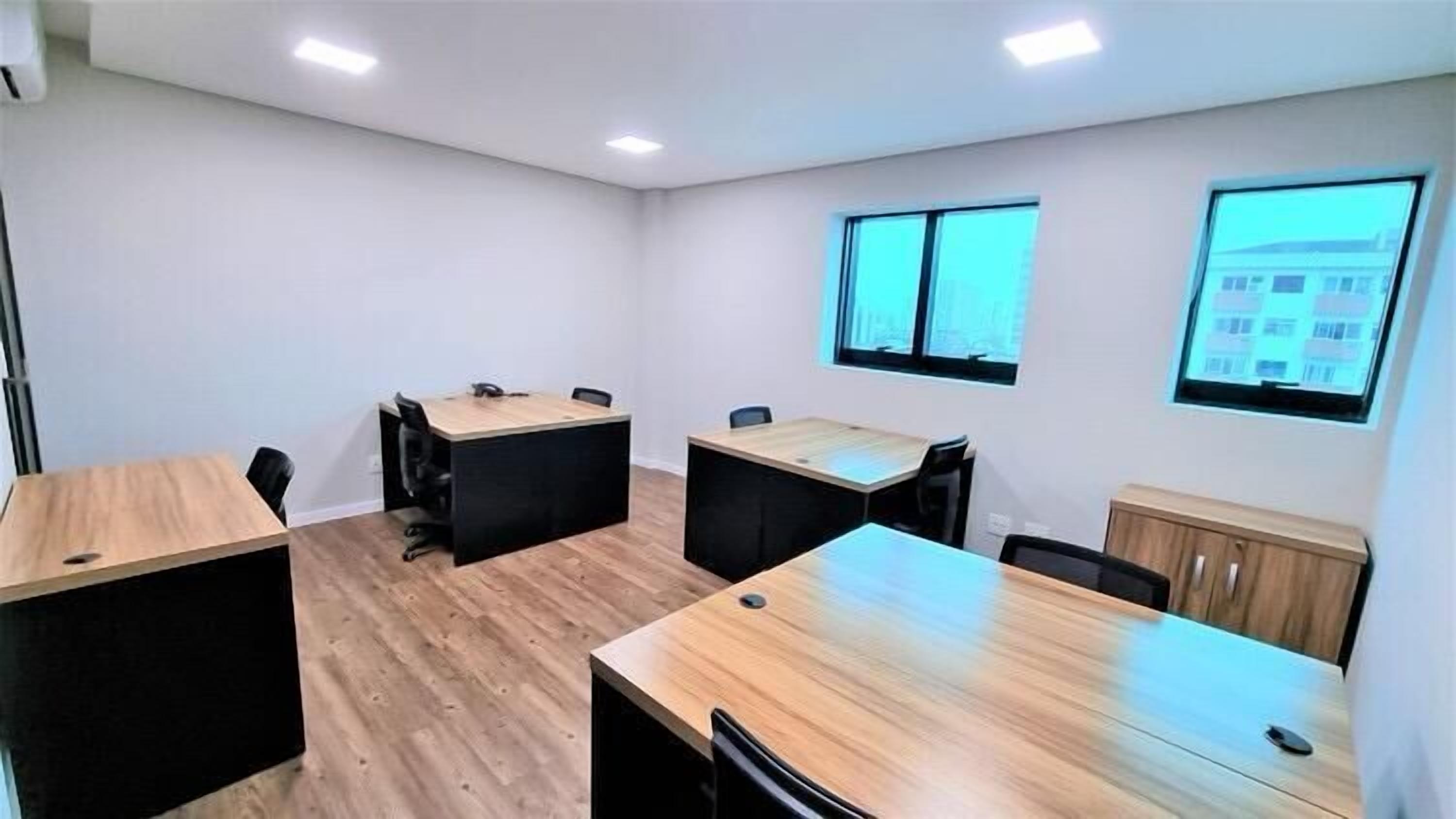 A conference room with three tables and chairs, white walls, and windows with a view of buildings.