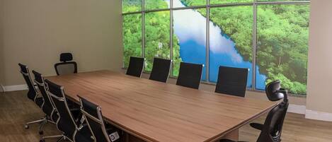 Una sala conferenze con un tavolo grande e sei sedie, ampie finestre con vista panoramica e una parete spoglia.
