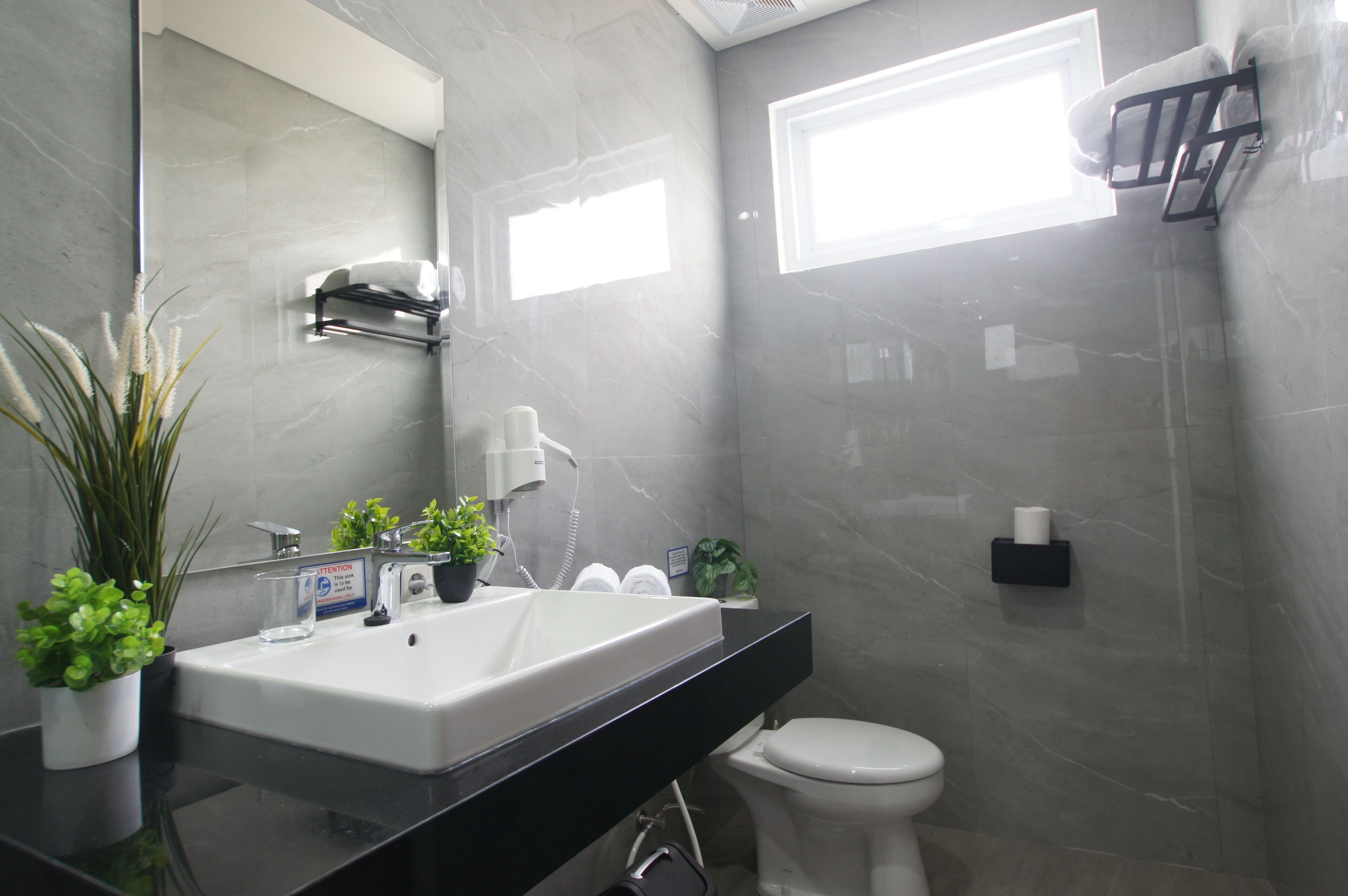 Un baño moderno con un lavabo blanco, un espejo, un inodoro y una zona de ducha.