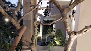 A modern outdoor area with a stone bench, potted plants, and a pathway leading to a building entrance. - Azura Villas Nusa Dua Bali (Nusa Dua)