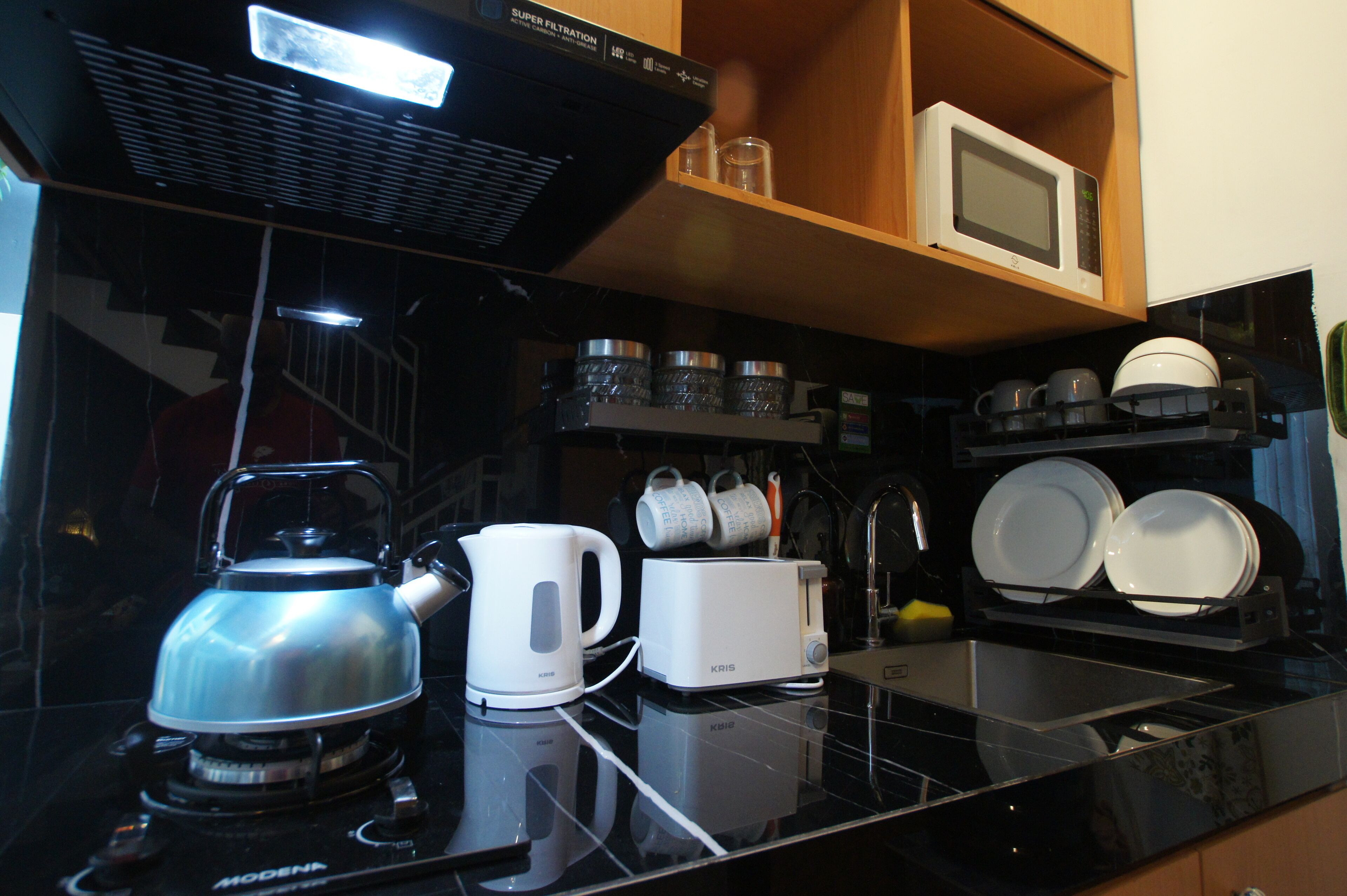 Eine moderne Küche mit schwarzem Arbeitsplatz, einem Wasserkocher, einem Toaster und einer Mikrowelle auf einem Regal.