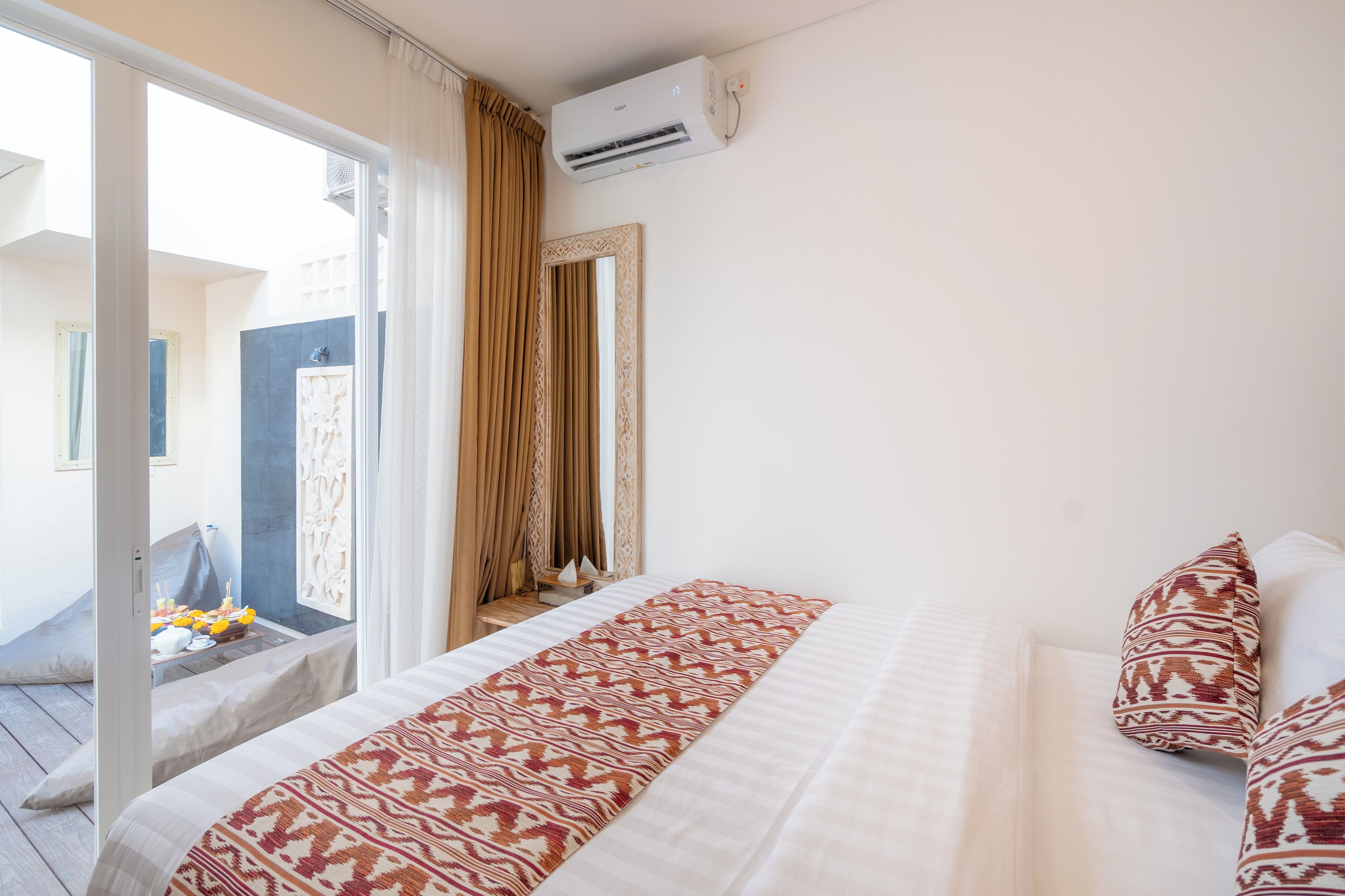 Ein Hotelzimmer mit Bett, einem Vorhangfenster, einer Klimaanlage und Blick ins Freie.
