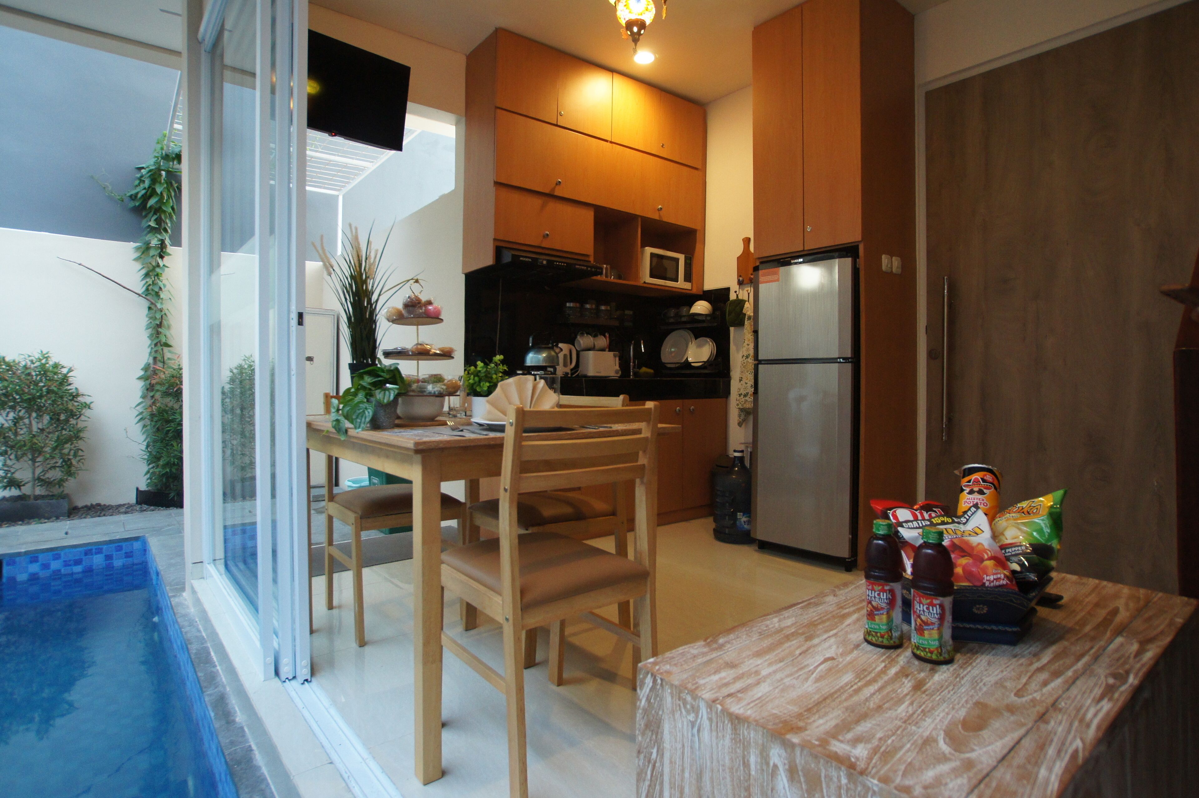 A compact kitchen with wooden cabinets, a refrigerator, and a dining area with a table and chairs.