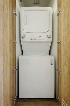 A compact, white, wall-mounted washer and dryer unit with a control panel featuring temperature and load settings. - Urbanista (Mexico City)