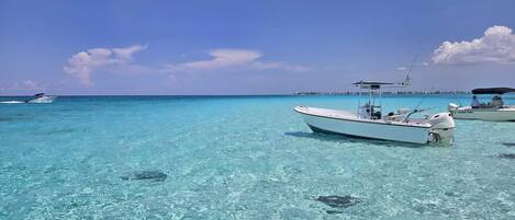 A clear turquoise sea with boats anchored, a distant shoreline, and a clear sky.