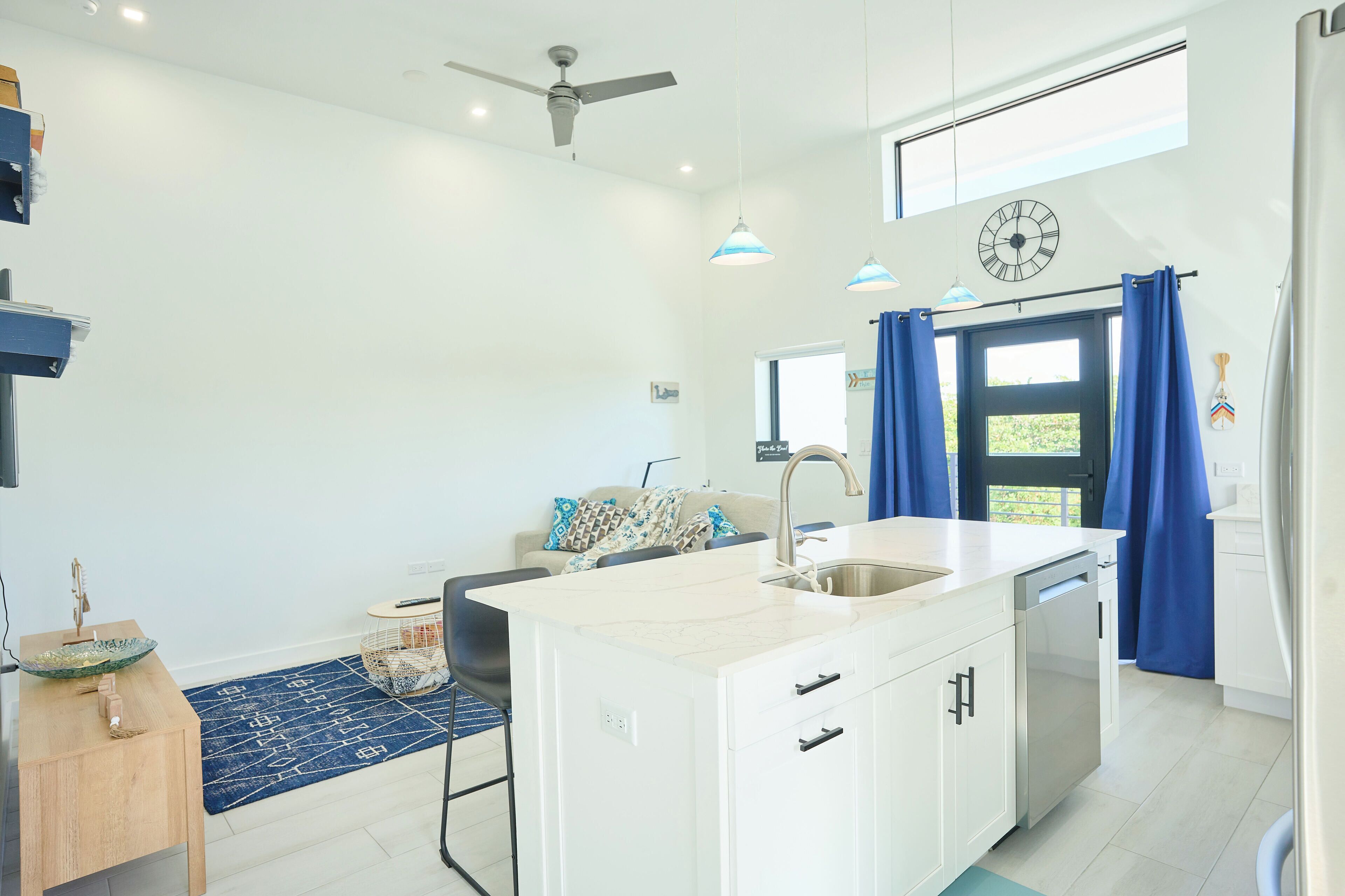 A modern kitchen with a central island, a built-in dishwasher, and a ceiling fan.