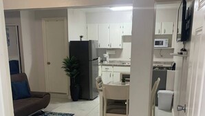 Um espaço compacto com cozinha compacta, área de refeições e sala de estar com sofá e mesa de centro.