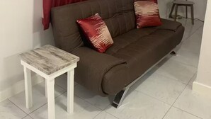 A living room with a brown sofa, two red pillows, a small white table, and a floor lamp. - The Castle ᴳ (Philipsburg)