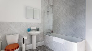 Une salle de bain avec des toilettes, un lavabo et une baignoire.