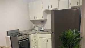 A compact kitchen with white cabinets, a stainless steel stove, a refrigerator, and a potted plant. - The Castle ᴷ (Philipsburg)