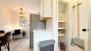 Una cocina moderna con armarios blancos, horno empotrado y comedor con mesa y sillas.