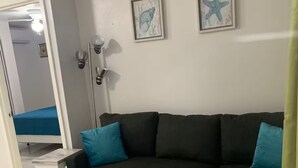 A living room with a dark brown sectional sofa, teal throw rug, and two framed wall art pieces. - The Castle ᴵ (Philipsburg)