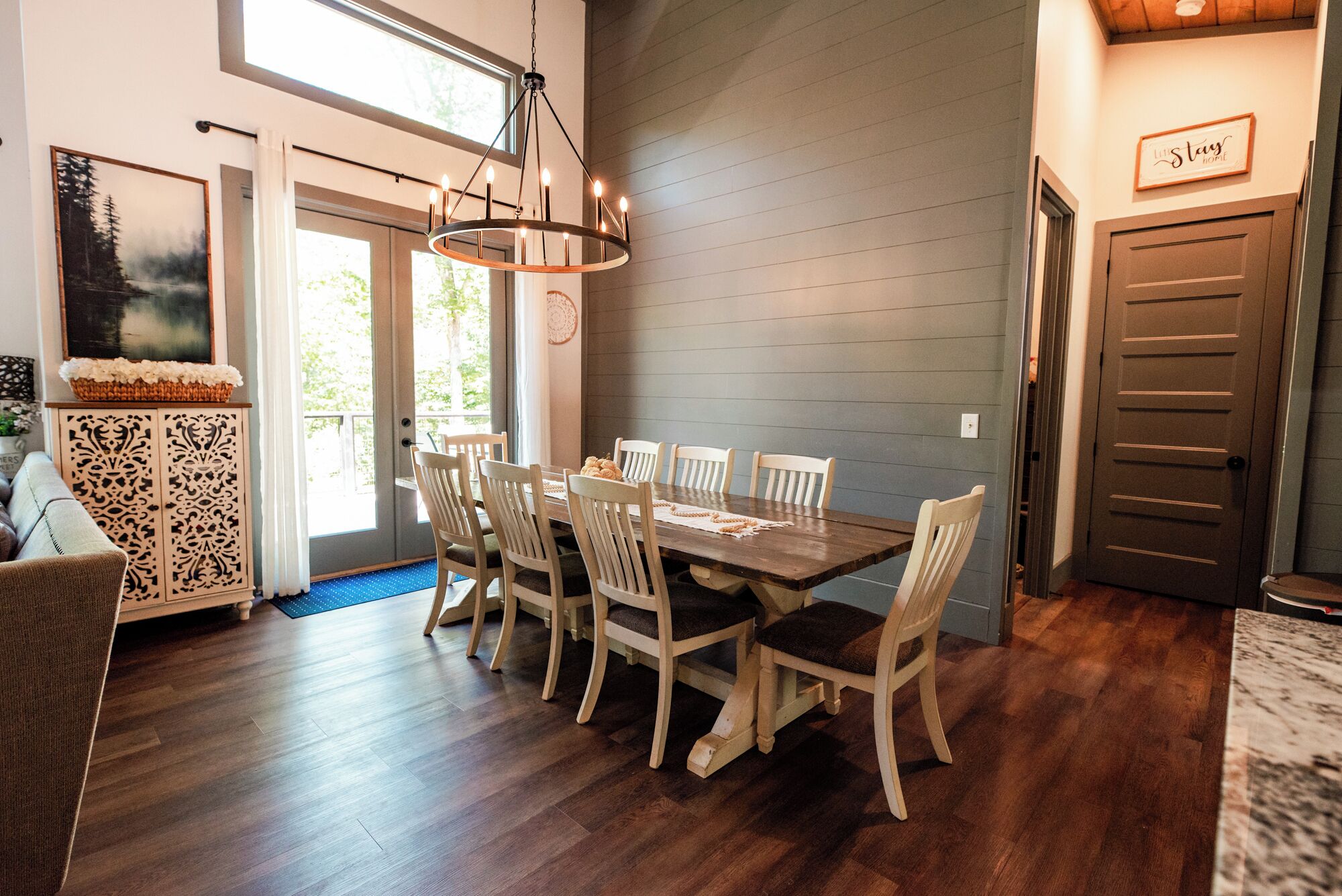 A dining area with a wooden table and chairs, a chandelier, and a door with a sign.
