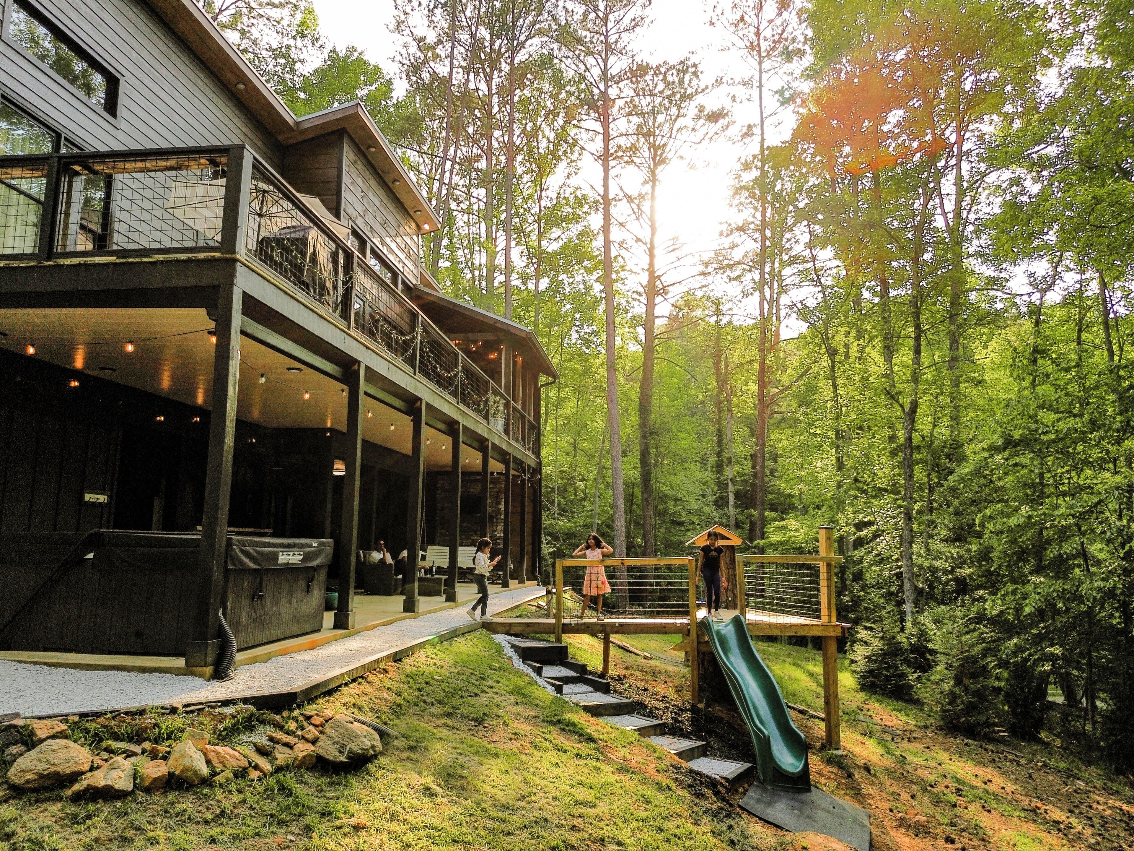 A two-story wooden building with a balcony, a slide, and a stone pathway.