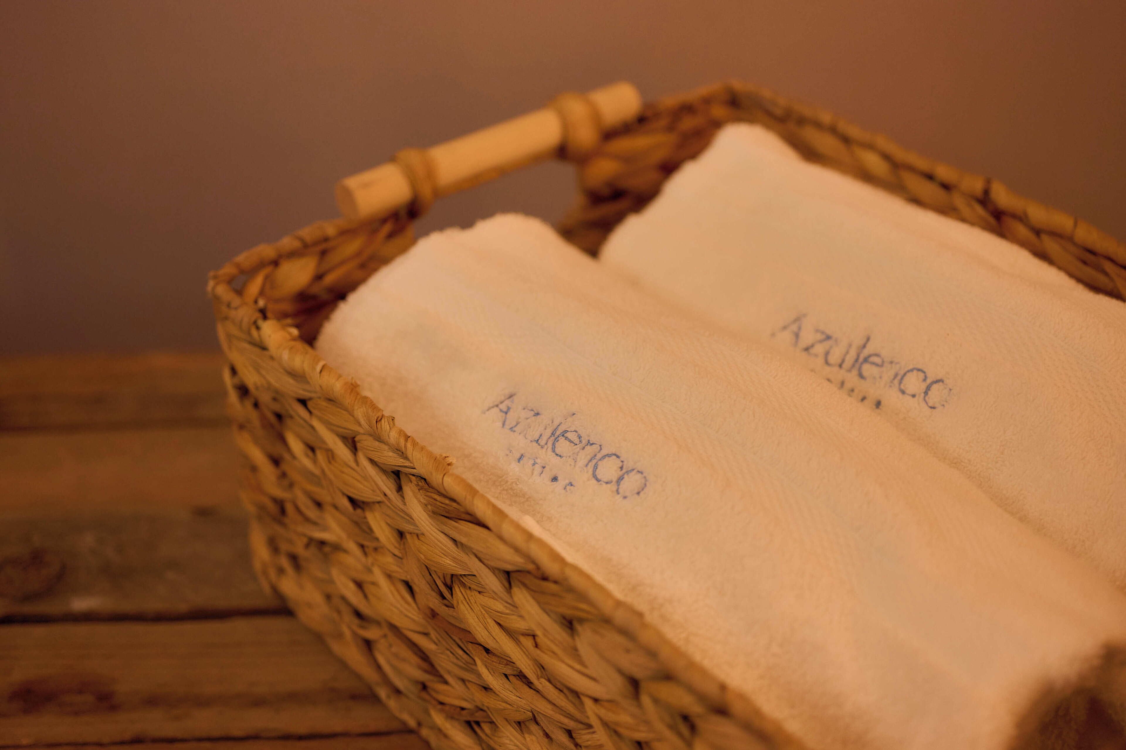 Una cesta de mimbre con dos toallas blancas que llevan la etiqueta 'Azulejo'.