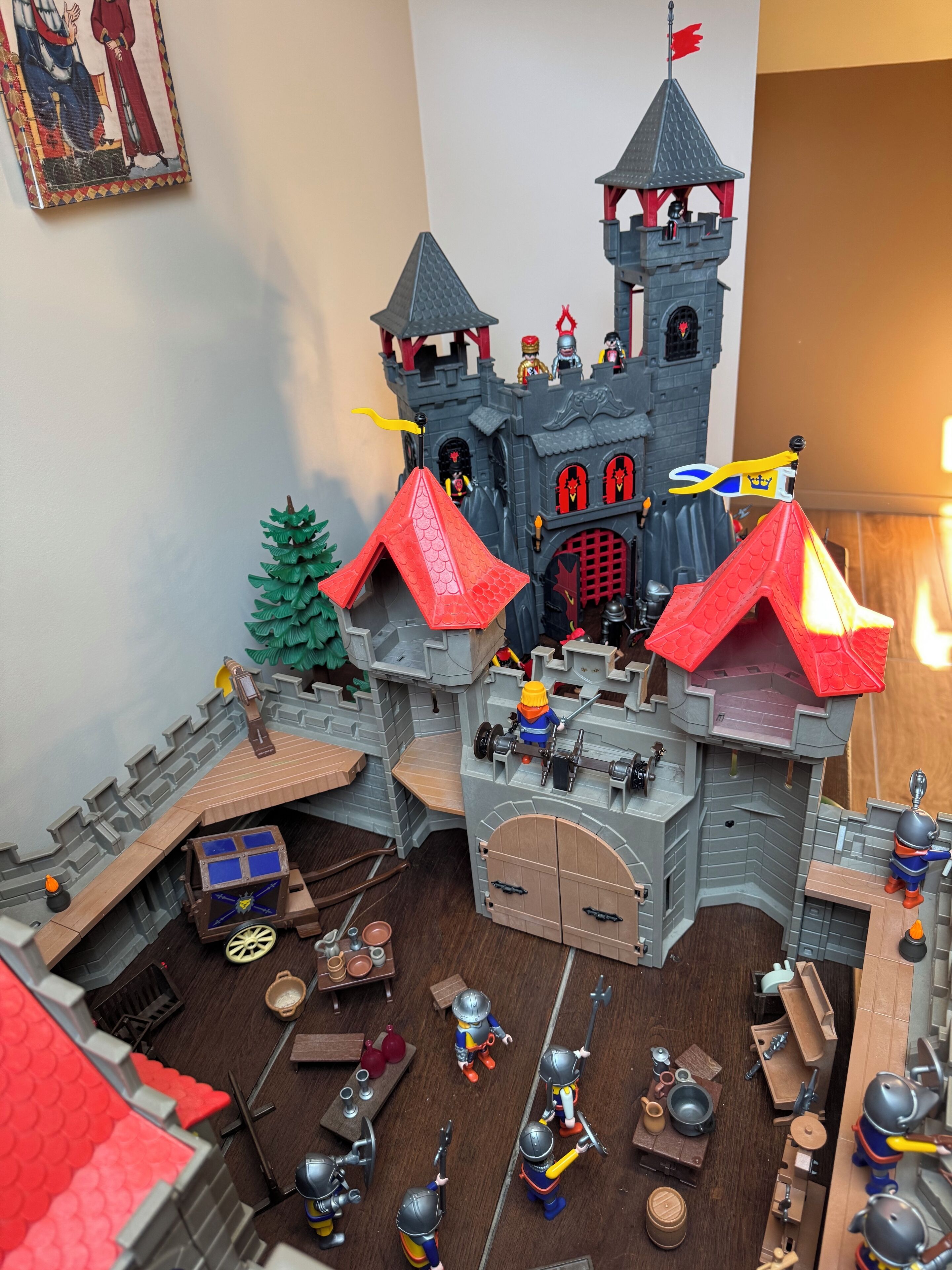 Een gedetailleerd model van een middeleeuws kasteel met meerdere torens, een centrale binnenplaats en diverse figuren en objecten.