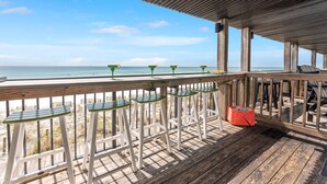 Eine Holzterrasse mit Geländer, die auf einen Strand blickt.
